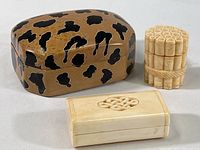 Three vintage carved trinket boxes including a large animal print stone box, a rectangular hinged box with carved design, and a round bamboo motif box