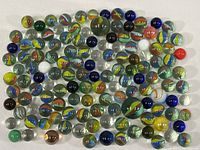 Full spread of approximately 100 marbles showing variety of colors, sizes and swirl patterns.