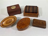 Group photo of five wooden boxes with different styles and finishes on a white surface