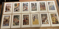 Photo of 12 portrait format animal and nature prints arranged on a table with cream matting. Images include voewl scenes with animals such as deer, birds, wolves, fish, and people interacting with nature.