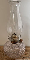 Full front view of the antique oil lamp showing the hobnail glass base, brass burner, and tall chimney