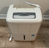 Front view showing air intake vents, control panel, water level indicator, power cord, and brand logo.