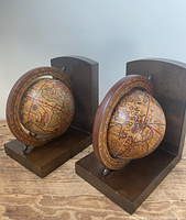 Pair of vintage-style spinning globe bookends with dark wood bases, showing side angle with globes and frames.