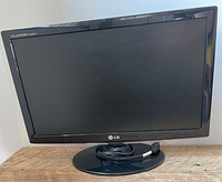 Front view of LG Flatron W1952TQ monitor, showing black bezel, screen, and circular base with cable coiled on stand.