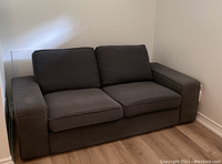 Front view of dark grey loveseat sofa with seat and back cushions in place
