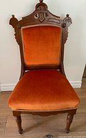 Front view of vintage wooden chair with orange velvet upholstery on seat and backrest, showing carved wood frame and turned legs.