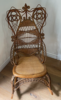 Front view of the wicker rocking chair showing woven backrest and cane seat.