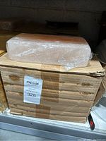 Stack of ten boxes containing Himalayan salt blocks, one block on top wrapped in plastic.