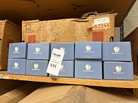 Ten boxed Wedgwood perfume bottles arranged on a wooden shelf, boxes are blue with Wedgwood white logo.