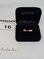 Ring seated in black velvet box bearing Macy's logo.