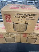 Boxes of three identical 2 liter glass ribbed pots stacked, showing front and side labeling