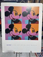 Full view of the Andy Warhol Mickey Mouse print showing the four colorful panels and the product title underneath. Print board edges visibly worn and curled.