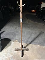 Full view of the wooden coat tree showing the square center pole with cross wooden legs base