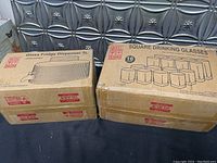 Two original boxes: one for the 5L glass fridge dispenser and one for 16 square drinking glasses, showing packaging and labeling.