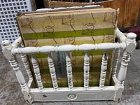 White painted wooden magazine rack with spindle sides and some paint chips, seen from the front with records inside