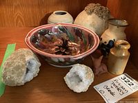 Full view of six artisan pottery pieces arranged with two geode halves showing crystalline interiors, all placed on a wooden surface.