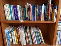 Two rows of assorted hardcover and softcover books on wooden shelves, titles visible vary from health, novels, science, and self-help.