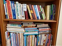 Books arranged on wooden shelves showing various cookbooks and guides with visible titles.