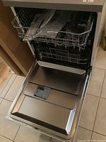 Dishwasher door open showing inner stainless steel tub and lower rack removed