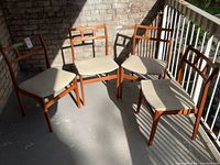 All four chairs arranged on balcony floor against brick wall