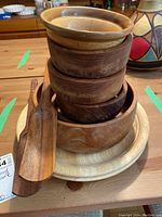 Stack of wooden bowls, plates, and two wooden serving utensils, showing variety of wood tones and sizes.
