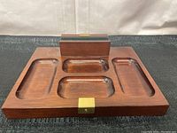 Front view of mahogany desk organizer showing three divided recessed trays and raised slot with brass accent.