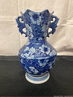 Front view of blue and white floral ceramic vase with winged handles showing detailed floral patterns and shaped neck.