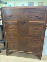 Full front view of the Art Deco chest showing the wood inlay chevron pattern and bakelite handles on the drawers.