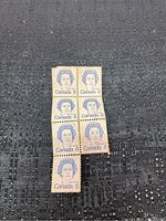 Close-up photo of 8-cent Canadian stamps featuring Queen Elizabeth II's portrait arranged in a vertical strip on a black textured surface.