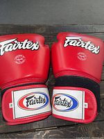 Front view of the pair of red Fairtex boxing gloves showing logos and wrist straps with size 16.