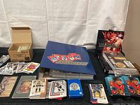 Full view of the collection showing blue binder labeled 'COLLECTION' with hockey card covers, a large cardboard box with hockey cards inside, multiple stacks of hockey cards arranged in front, and unopened hockey card packs on right side.