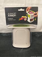 Front view of Joseph Joseph ChopCup vegetable chopper in original packaging, showing the white and green design.