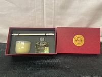 Open red box displaying candle, bottle of oil, and diffuser sticks inside.
