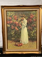 Framed canvas print titled The Rose Garden showing a woman in a white dress among rose plants, signed by the artist.