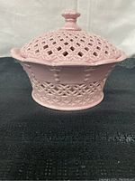 Side view of pink ceramic vintage covered bowl showing detailed lattice openwork and scalloped rim.