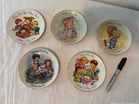 Five vintage Avon Mother's Day collectible plates with colorful children's illustrations. Plates have titles such as 'The Day We Said', 'Loving Is Caring', and 'Playing For Love' from 1987, 1988, 1989.