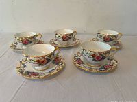 Front view of 5 cups and matching saucers featuring floral pattern and gold trim