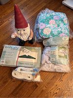 Photo shows a 22-inch tall garden gnome, set of six floral padded chair cushions, green gazebo fabric top, net curtain for sun shelter, white lawn chair webbing.