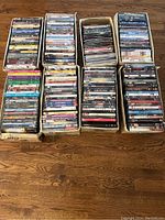 Eight boxes filled with DVD movies arranged standing upright, showing a variety of titles on their spines in different colors and styles.