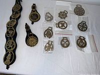 Photo of the collection of vintage decorative horse brasses including those mounted on leather straps and others individually packed in plastic bags.