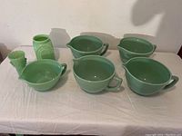 Seven-piece grouping of bowls and vases on white cloth, frontal view