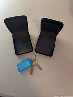 Two open black jewellery boxes next to keys for size reference, showing the felt interior and hinged lids.