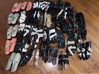 Overview of over 50 pairs of women's shoes arranged on floor, showing various styles in black, white, pink, beige, and other colors.