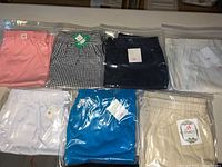 Seven pairs of ladies shorts in various colors including pink, blue, white, beige, black, and checkered pattern, folded and sealed in plastic bags.