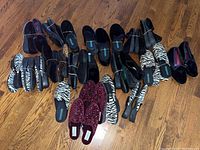 Overview of all slippers on hardwood floor showing quantity and variety including zebra print and velvet styles.