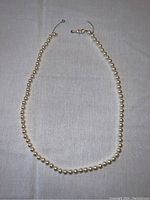 Full view of the pearl necklace laid out, showing length and pearls