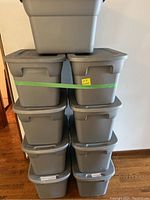 Stack of nine gray plastic storage bins with lids