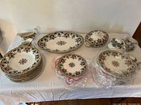 Full view of laid out Ravenscliffe china set on white cloth showing plates, bowls, cups, covered serving pieces, and gravy boat.