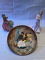Front view of Royal Doulton Balloon Seller plate with two dolls in background
