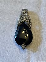 Front view of the vintage sterling silver brooch showing black teardrop stone with marcasite decoration.